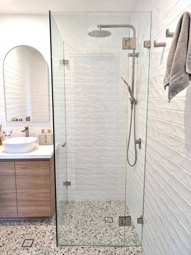 Frameless shower screen with brushed nickel hardware and white subway tiles