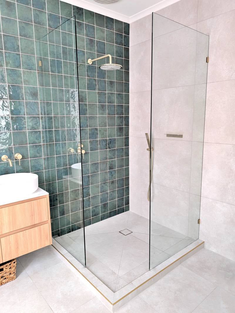 Corner access walk in shower with a green feature wall