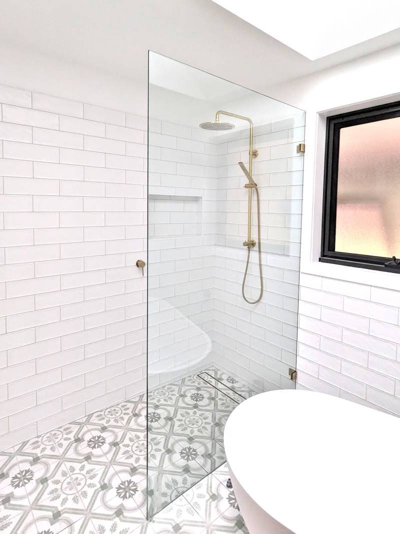 Walk in shower with white subway tiles and gold fittings