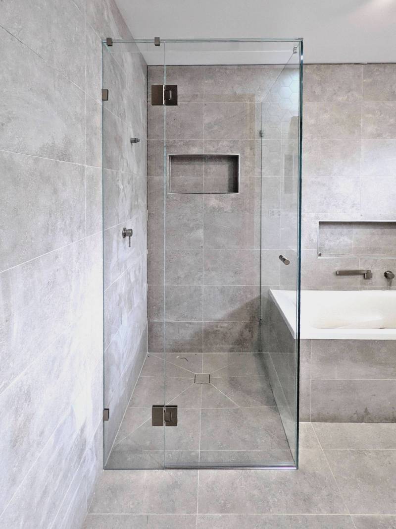 Corner shower screen in bathroom with grey tiles