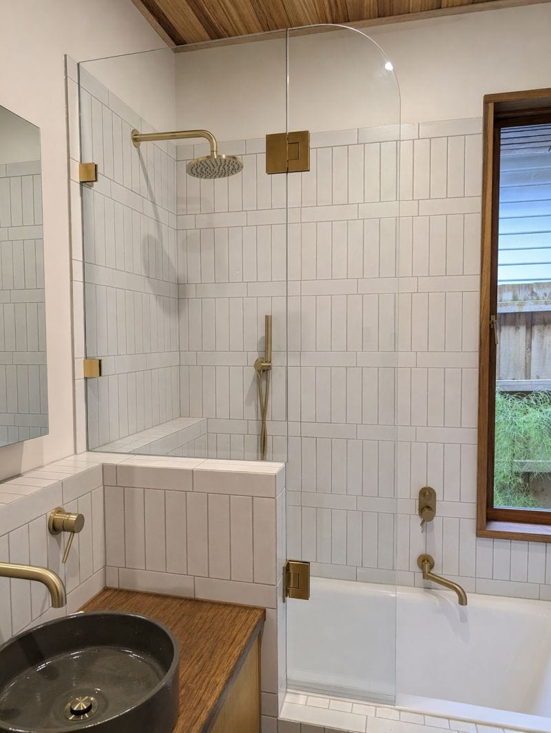 Over-bath shower screen with brushed brass fittings