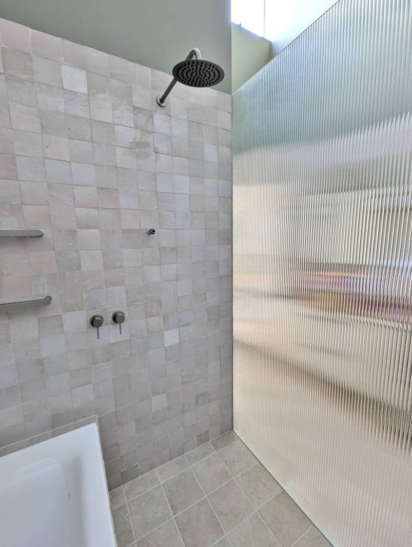 Reeded glass shower panel and small handmade square tiles