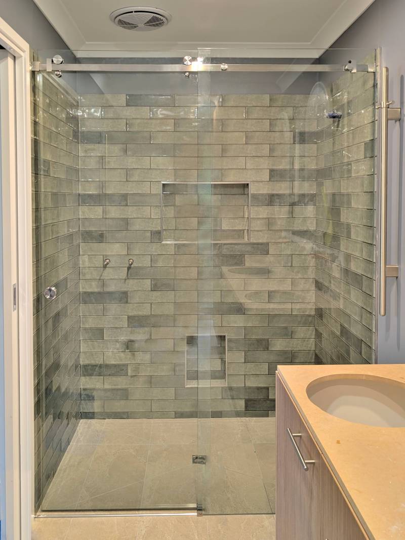 Sliding frameless shower screen with chrome hardware in a Gisborne bathroom