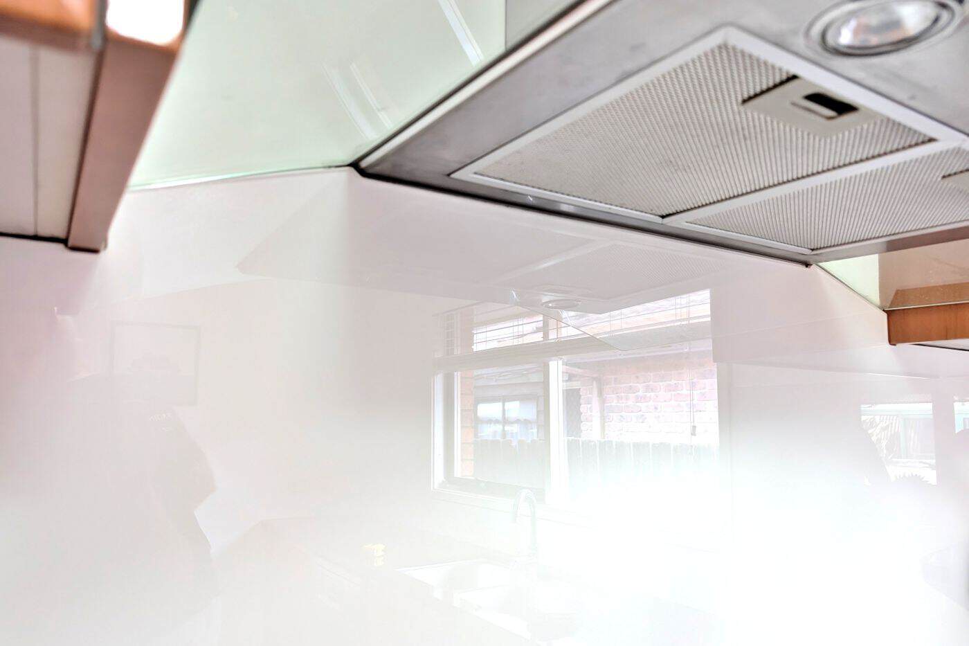 Custom white glass splashback installed around a kitchen rangehood