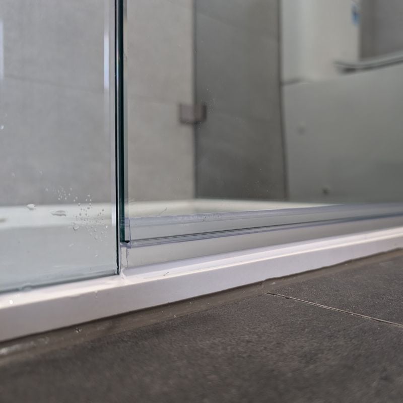 A close up of a frameless shower screen door seal