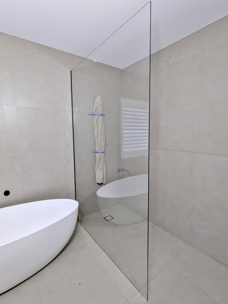 Large fixed frameless shower panel installed in Greenvale