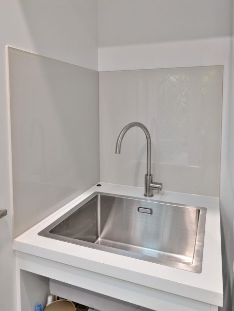 Light grey glass splashback in a compact Carlton North laundry