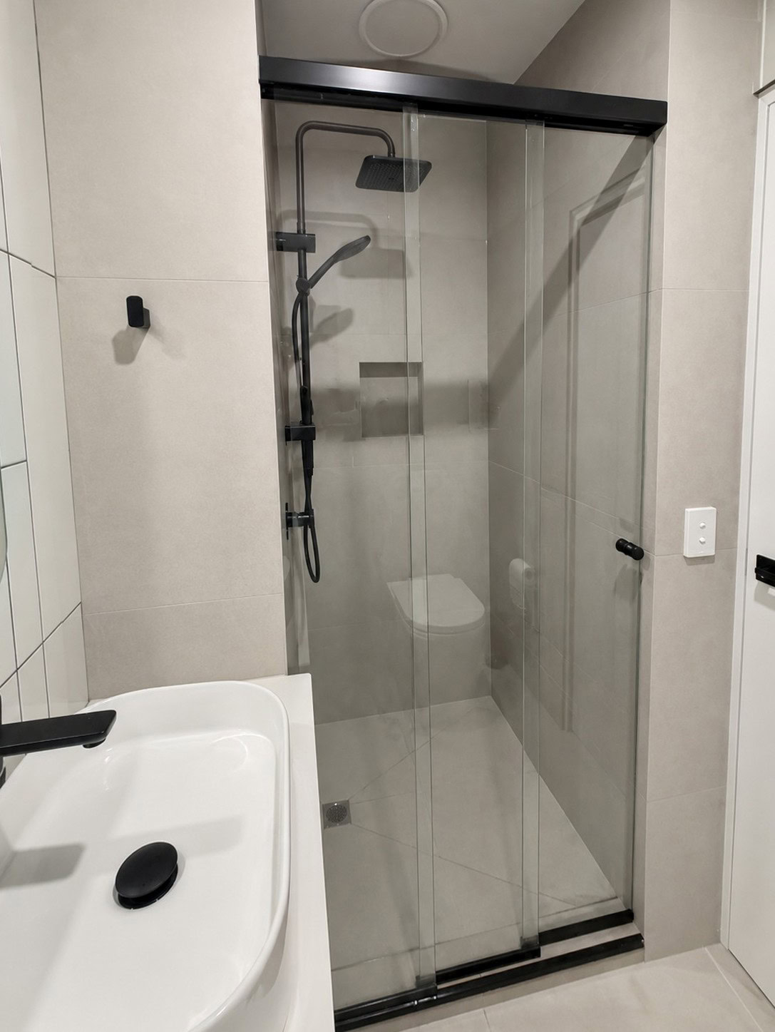 Three panel sliding shower screen with black hardware installed in Taylors Lakes