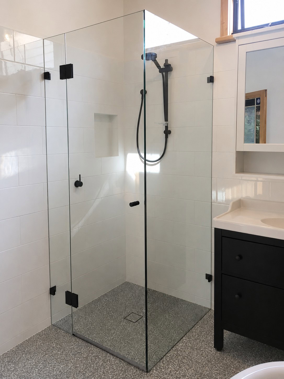 Frameless shower screen with black hinges installed in Newport bathroom