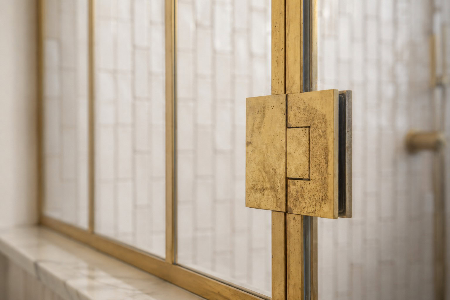 Rear ensuite raw brass shower screen with shorter glass panel above the tiled nib