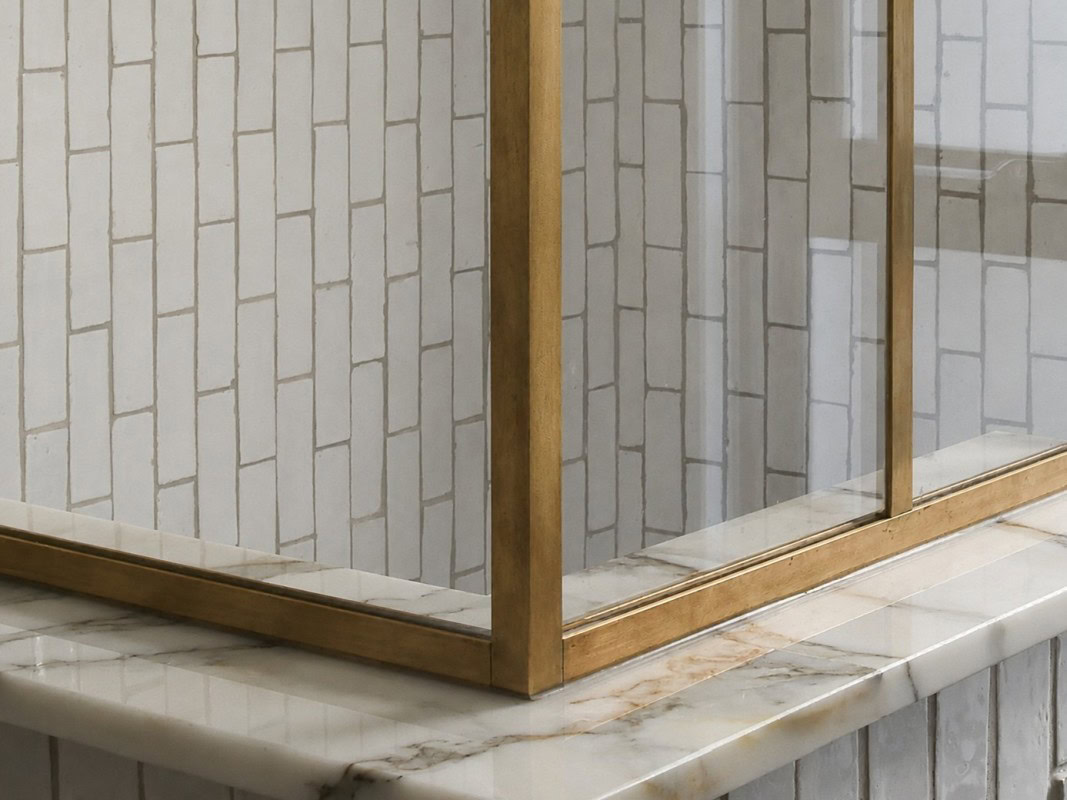 Close-up of raw brass corner detail meeting low-iron glass