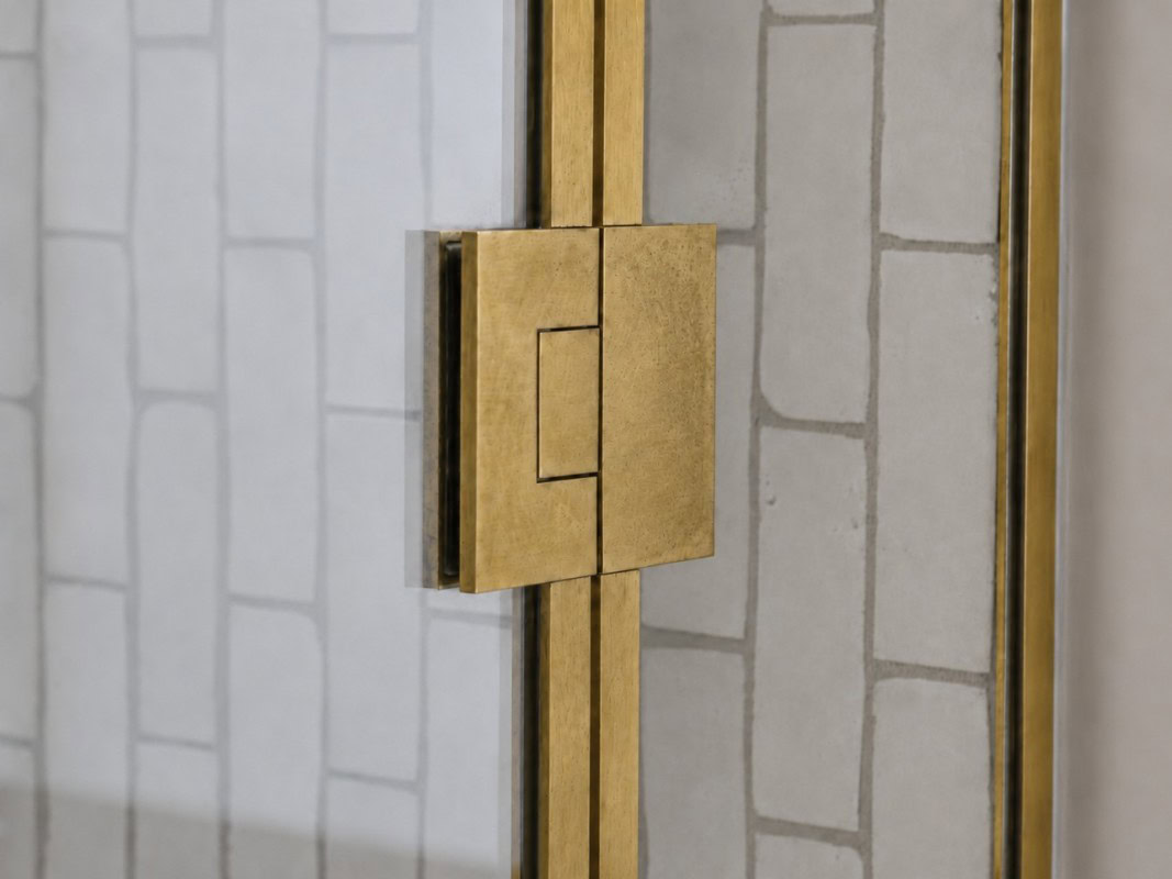 Close-up of heavy-duty shower screen hinge with raw brass cover plates