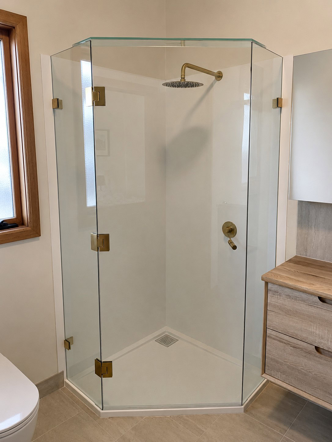 Brushed gold frameless shower screen installed in Maddingley bathroom