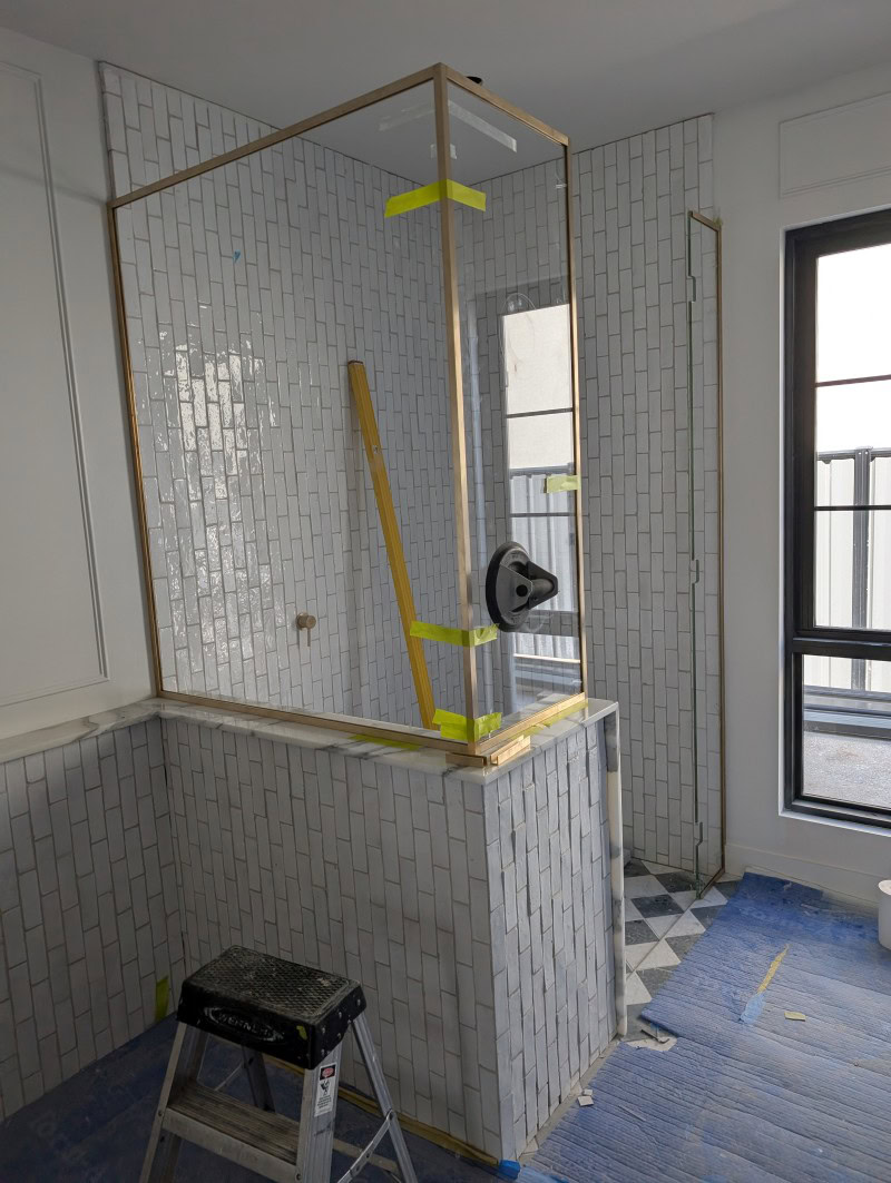 Main bathroom raw brass shower enclosure during installation