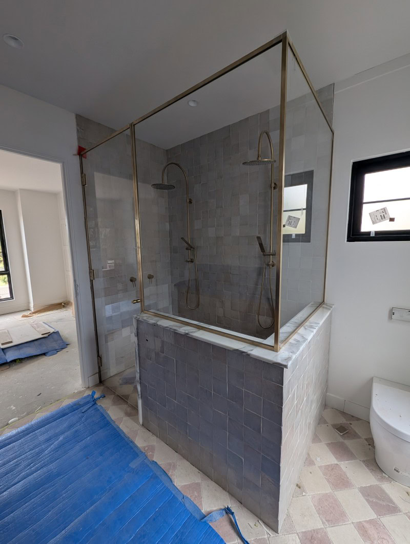 Front ensuite raw brass and low iron glass shower screen installation in progress