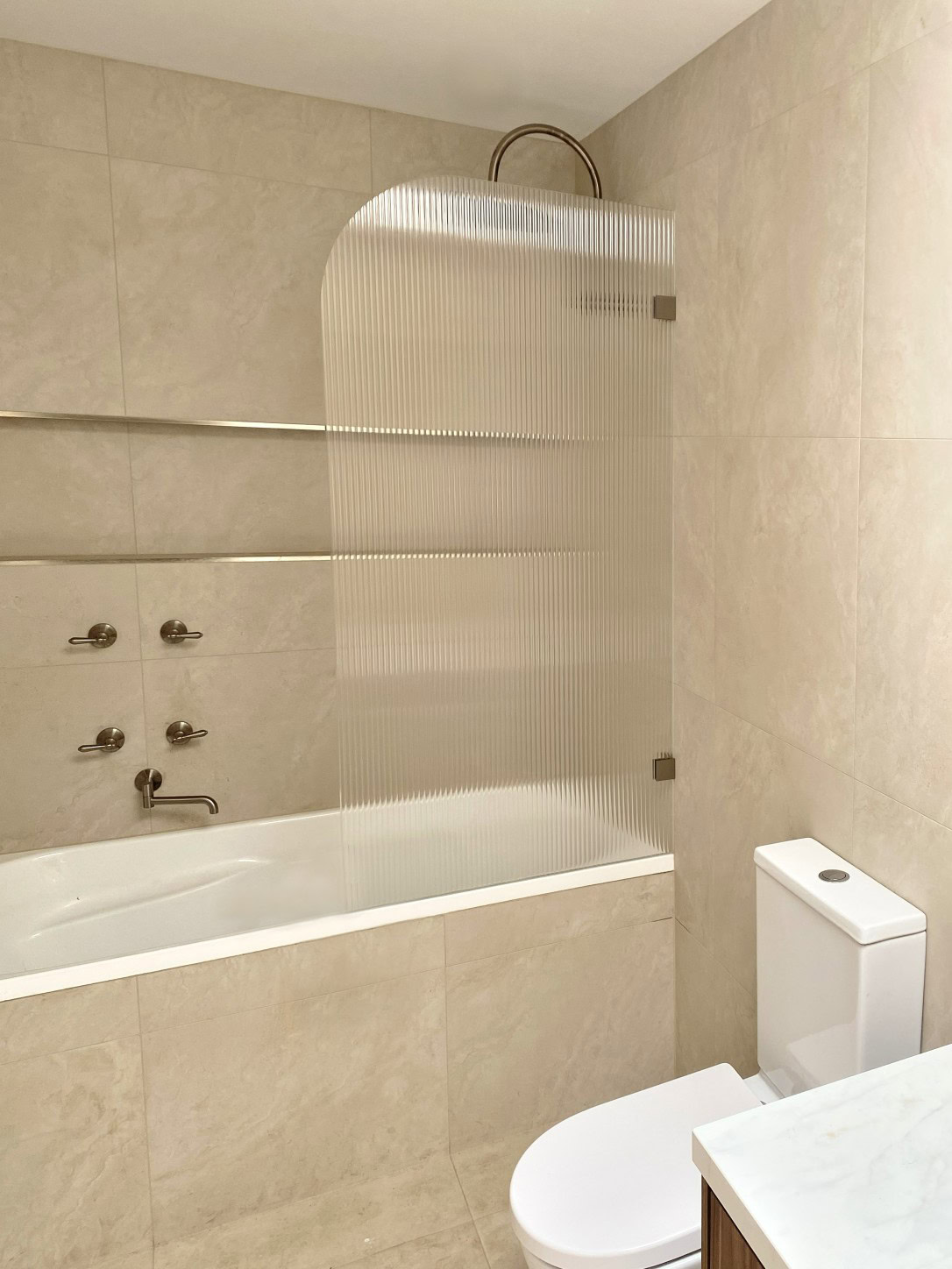 Over bath reeded glass shower screen with brushed nickel hardware installed in Newham bathroom