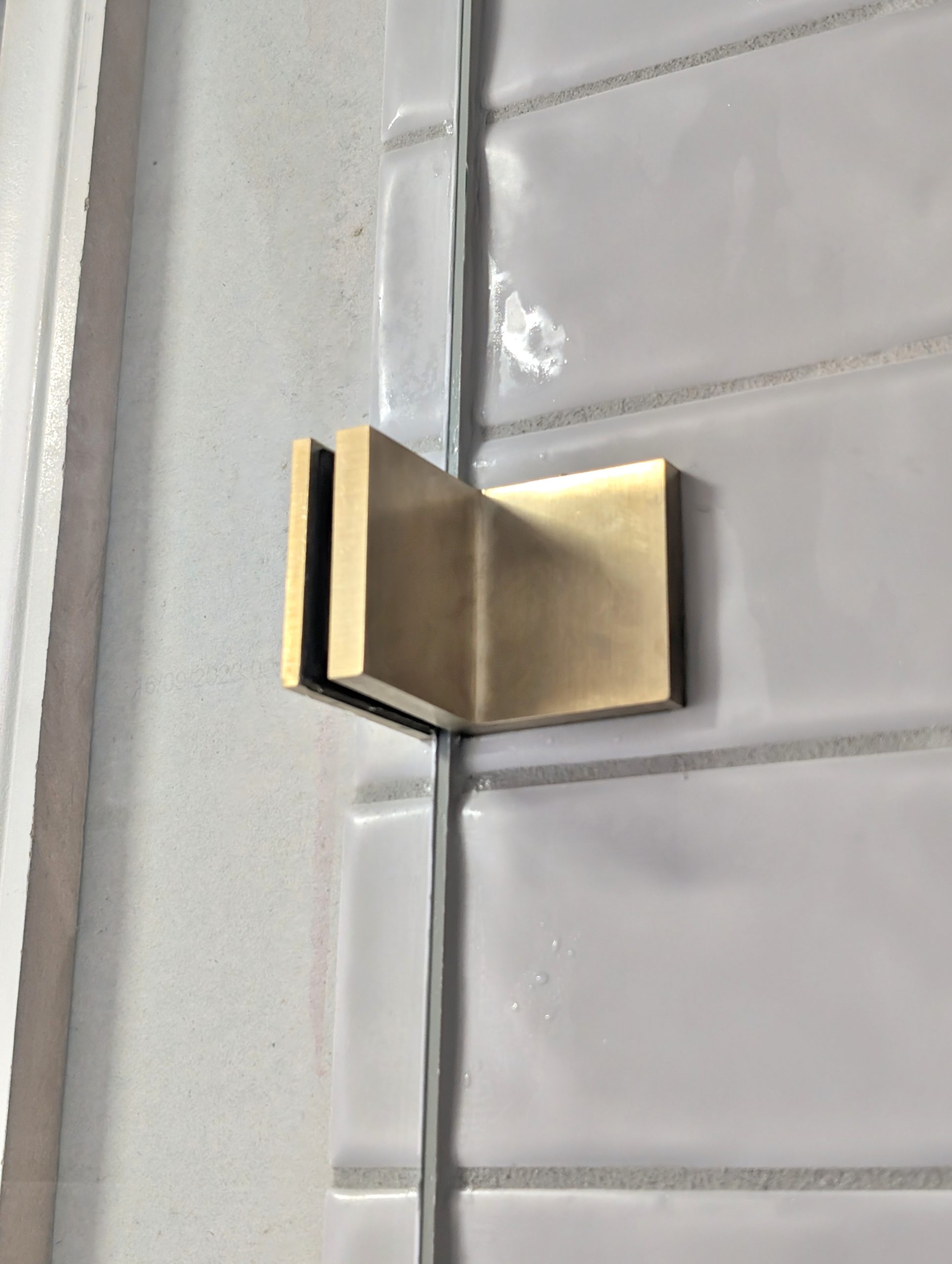 Brushed brass shower screen bracket fitted to frameless glass